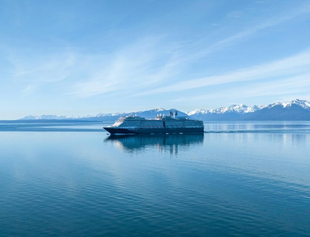 A cruise ship sails through serene waters with snowcapped mountains in the background in Hoonah, Alaska.